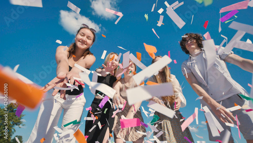 Group of cheerful high school students throwing colorful confetti in the air, celebrating graduation or end of school year