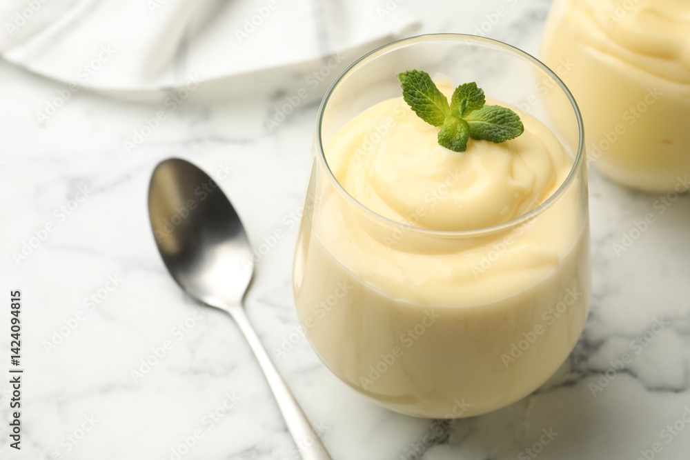 Tasty vanilla pudding with mint served on white marble table, closeup Tasty vanilla pudding with mint served on white marble table, closeup