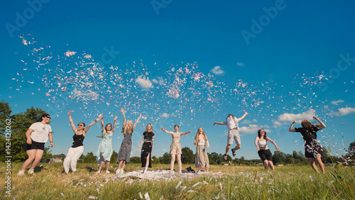 Group of joyful high school students throwing confetti in a summer field, celebrating graduation or end of school year