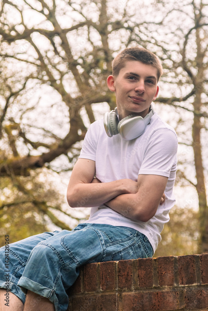 Obraz premium Teenage boy sitting on a brick wall