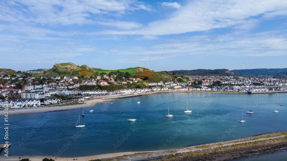 Fototapeta premium Aerial view of small sailing craft on River Conwy with town of Deganwy on opposite shore