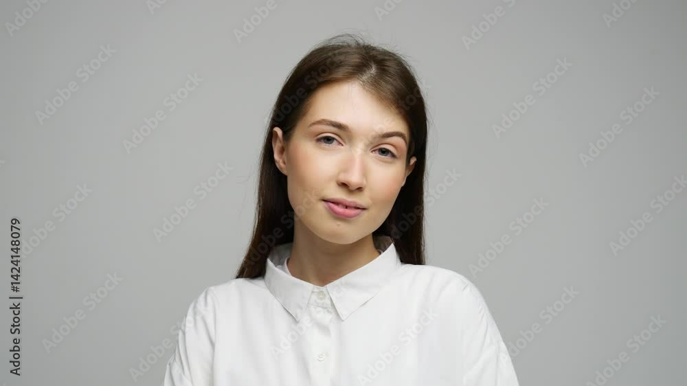 Confident young woman with brown hair in a crisp white shirt, exuding modern elegance. Confident young woman with brown hair in a crisp white shirt, exuding modern elegance.