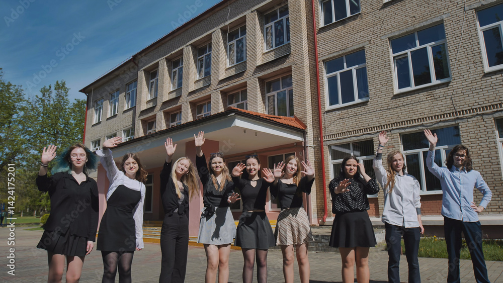 Fototapeta premium Students happily waving in front of school building on sunny day, celebrating friendship and togetherness