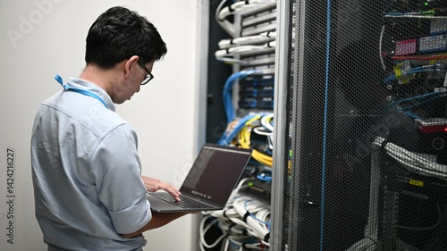 Computer engineer is setting up network in server room,Systems Maintenance Technician,Male engineer working in server room at modern data center	
