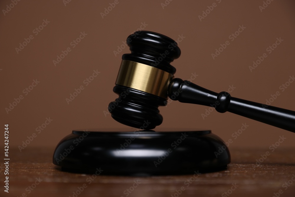 Judge's gavel and sound block on wooden table against brown background, closeup Judge's gavel and sound block on wooden table against brown background, closeup