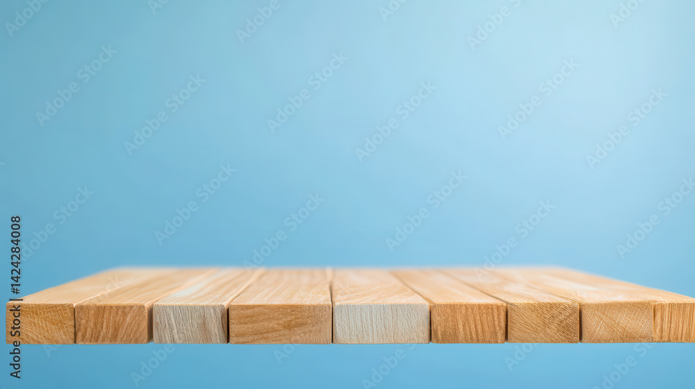Fototapeta premium Wooden blocks are arranged in a straight line against a solid light blue background, creating a simple and clean composition that suggests stability and order.