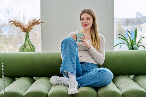 Obraz na płótnie Portrait of relaxed beautiful young woman sitting at home on sofa with cup w salonie
