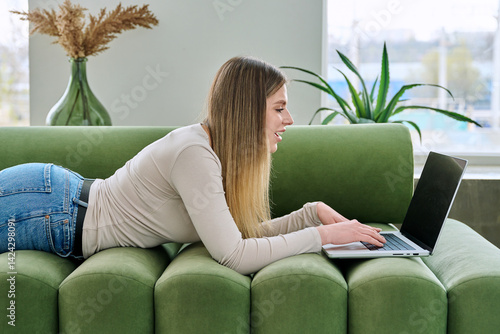 Obraz na płótnie Young woman lying on sofa at home using laptop w salonie