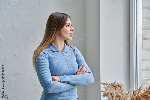 Obraz na płótnie Young confident beautiful woman with crossed arms looking out the window w salonie