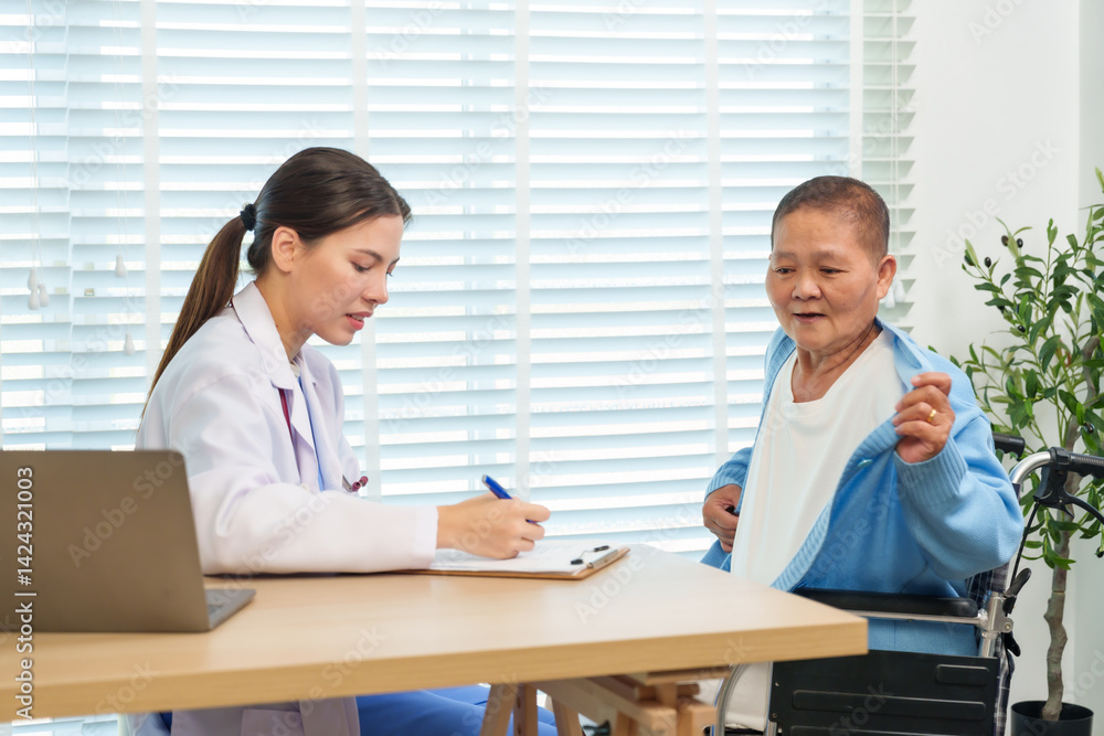 Asian senior woman sitting in wheelchair lifting cardigan during medical consultation with female doctor writing on clipboard, showing health checkup interaction and elderly patient care in hospital. Asian senior woman sitting in wheelchair lifting cardigan during medical consultation with female doctor writing on clipboard, showing health checkup interaction and elderly patient care in hospital.