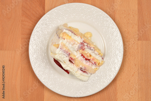 Obraz na płótnie A slice of Frozen wind cake (layered meringue cake with whipped cream and fruit) is presented on a white ornate plate w salonie