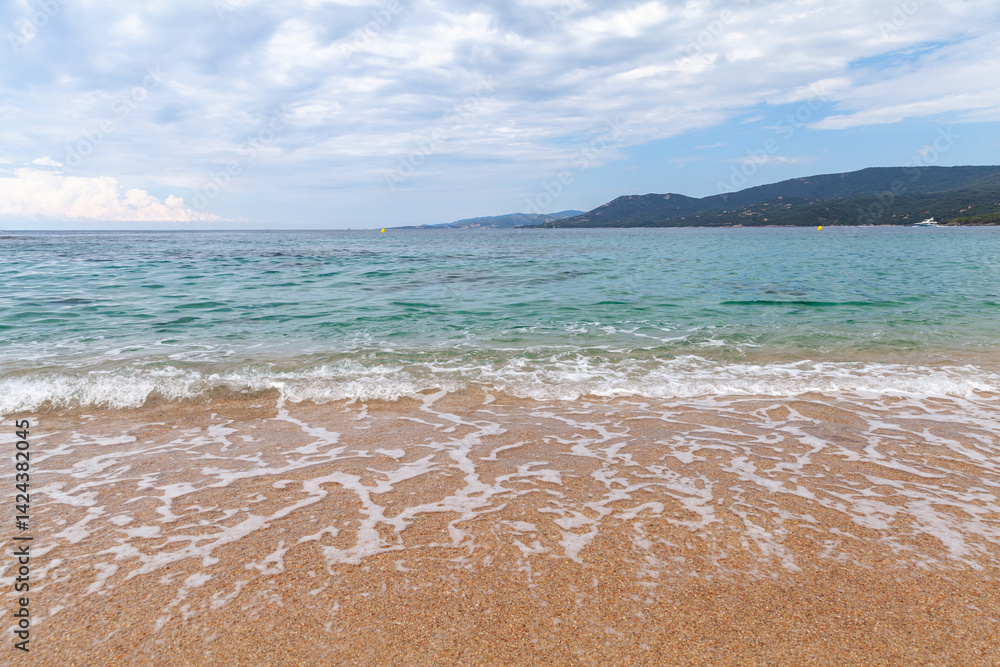 Tranquil beach scene featuring soft waves lapping sandy shores with hills