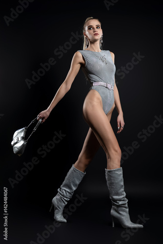 Fashion portrait of beautiful model in silver top and boots and silver jewelry