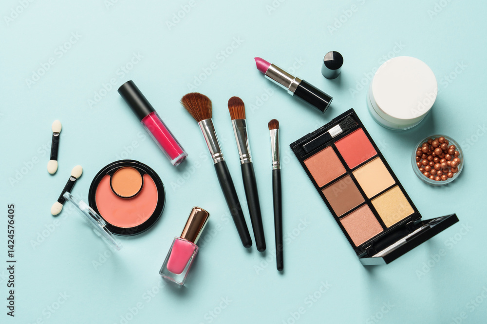 Beauty products on blue background. Cosmetic palette, brushes, cream and lipsticks. Top view.