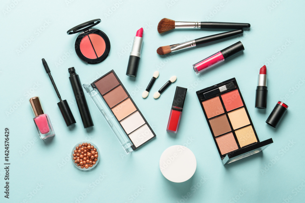 Make up products on blue background flat lay. Cosmetic palette, brushes, cream and lipsticks.