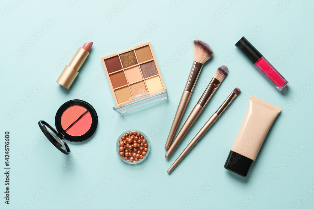 Beauty products on blue background. Cosmetic palette, brushes, cream and lipsticks. Top view.