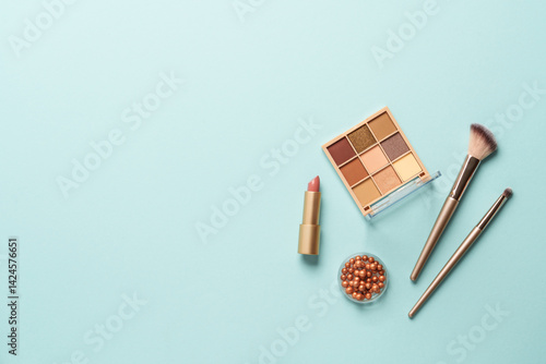Obraz na płótnie Make up products on blue background. Cosmetic palette, brushes and lipstick. Top view with copy space. w salonie