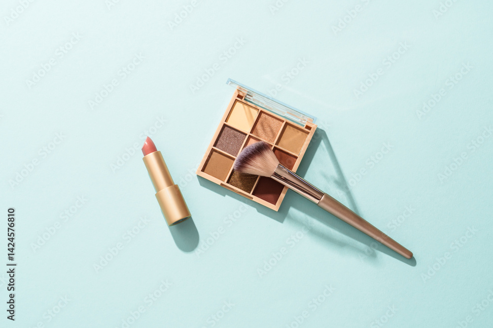 Make up products on blue background. Cosmetic palette, brushes and lipstick. Top view with copy space.