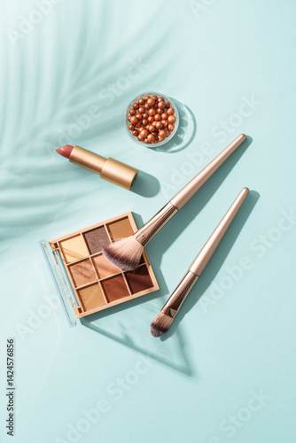 Make up products on blue background with shadows. Cosmetic palette, brushes and lipstick.