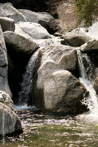 Smooth rocks shaped by water erosion with a gentle flow of clear stream running over them. A quiet, intimate view of a mountain creek. Perfect for calmness, geology, and eco themes.

