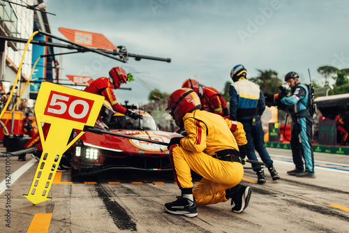 Team Mechanics refuel During a High-Speed Pit Stop in the Midst of an Endurance Race. Supercar do a inspection on pit lane during race