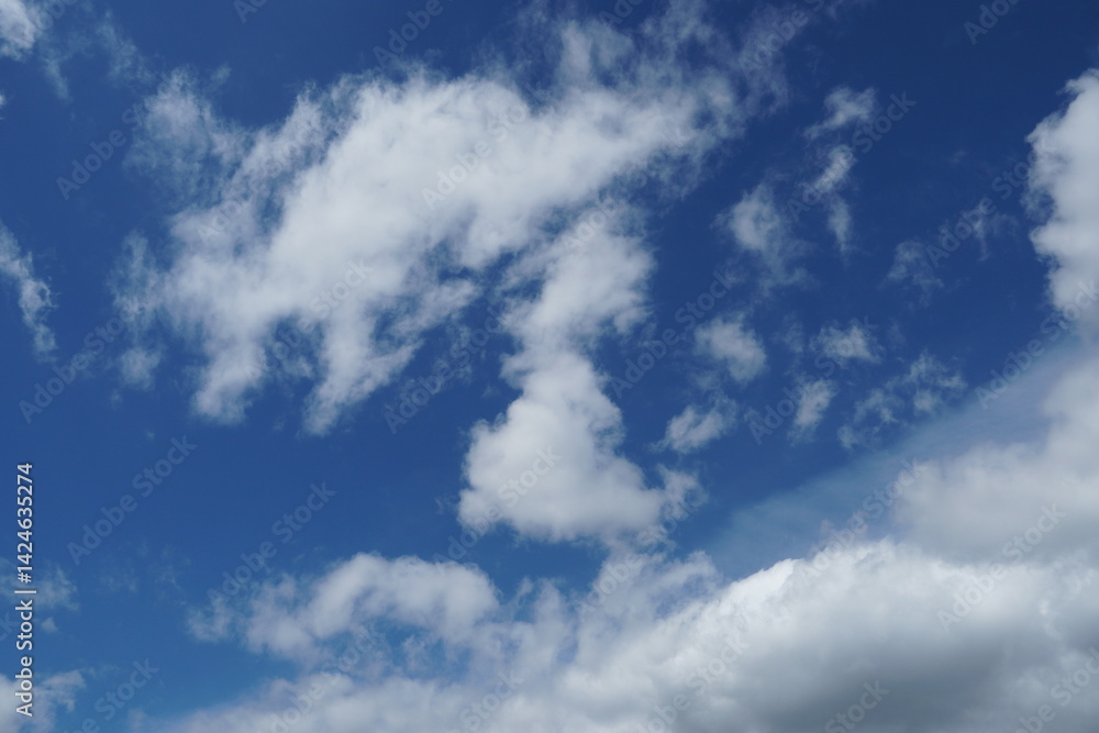 White fluffy clouds in the sky. Blue sky and cloud cover on a sunny summer day. Empty background, copy space White fluffy clouds in the sky. Blue sky and cloud cover on a sunny summer day. Empty background, copy space