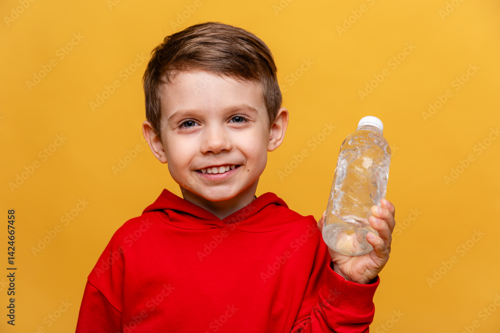 A happy little boy drinks water for health on yellow background. The child is holding a water bottle. A kid with a plastic bottle. Children's activity and energy, generation Z. body hydration concept