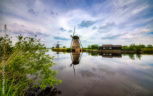 Fotografie Canal and Old, Charming Windmills Reflecting in the Water in Kinderdijk, Netherl