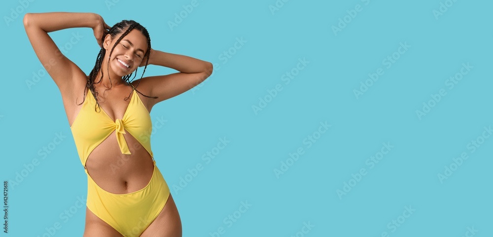 Beautiful young African-American woman in stylish swimsuit on light blue background with space for text
