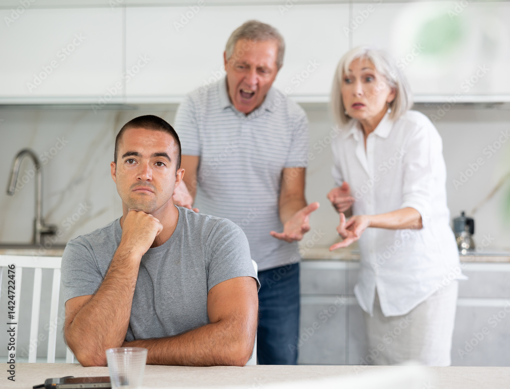 Obraz premium Couple of elderly man and woman during family quarrel with adult man in kitchen