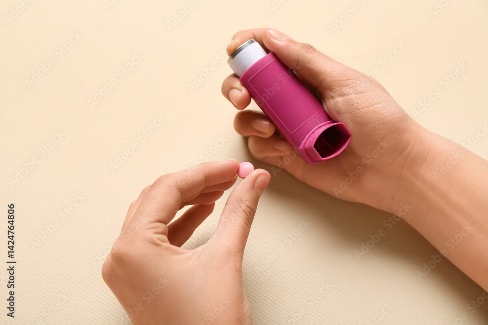 Child's hands with asthma inhaler and pill on beige background