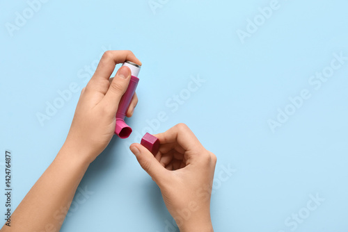 Child's hands with asthma inhaler on blue background