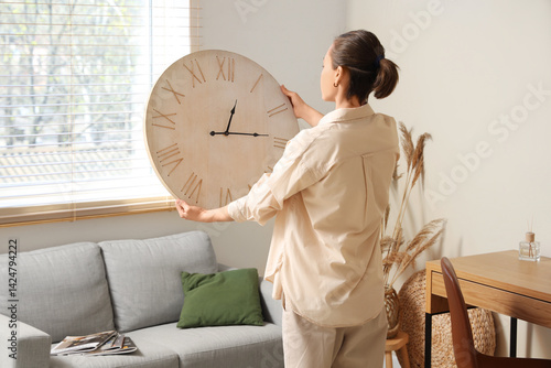 Obraz na płótnie Young woman holding clock near sofa in living room w salonie