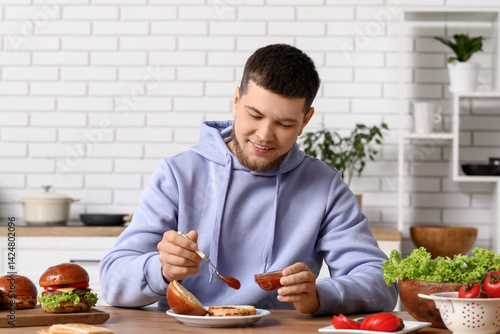 Young man putting ketchup o...