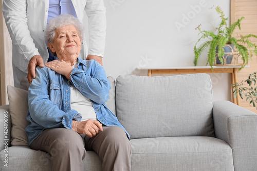 Obraz na płótnie Senior woman with doctor sitting on sofa at home w salonie