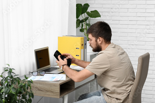 Young man in debt with empt...