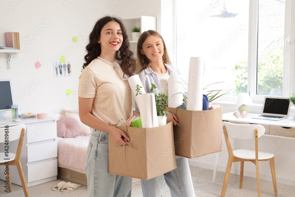 Female students with cardboard boxes in dorm room on moving day