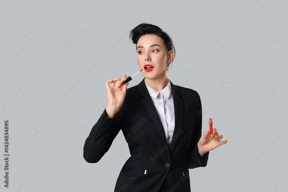 Young pin-up stewardess applying lipstick on light background