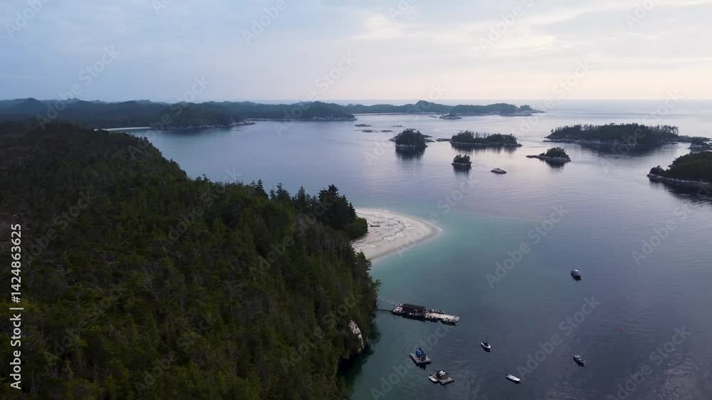 Aerial view over Calvert Island, British Columbia. Flying towards a solitary beach, a dock and boats moored below