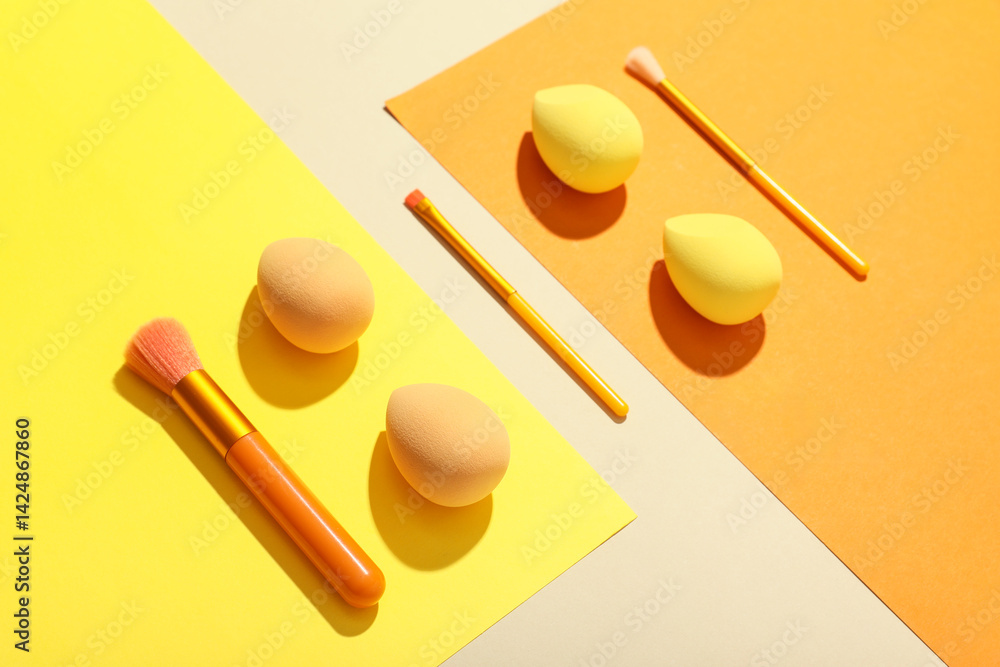Makeup sponges and brushes on colorful background