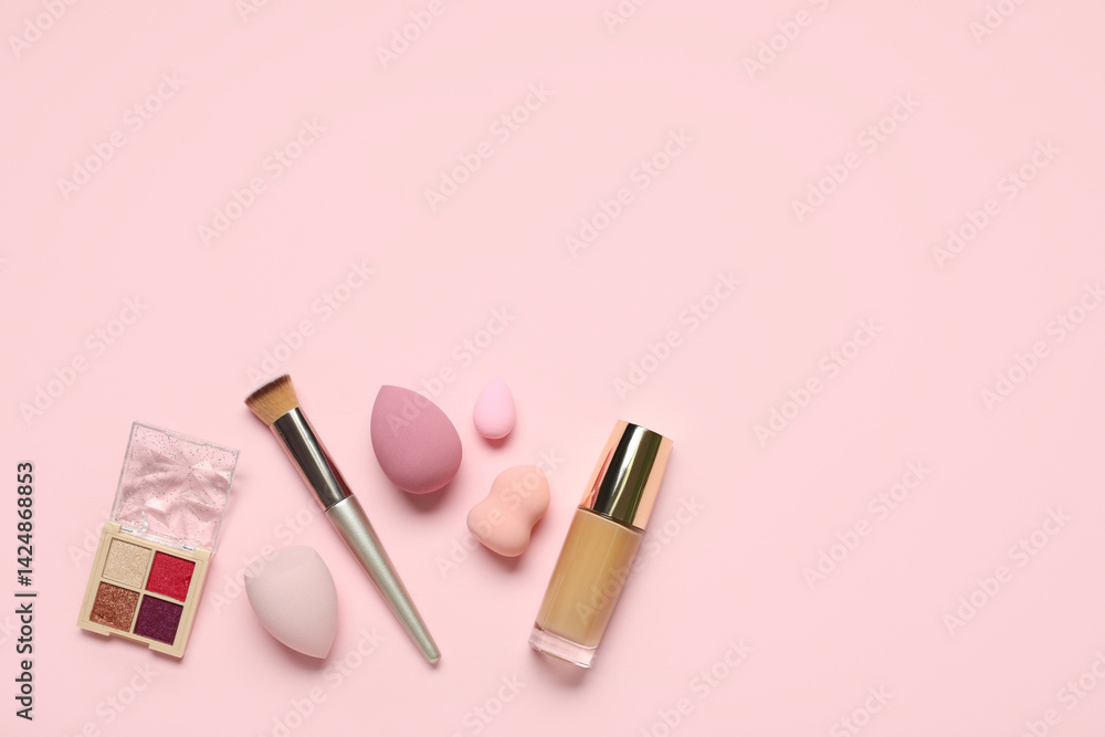 Makeup sponges with brush, foundation and palette of eyeshadows on pink background