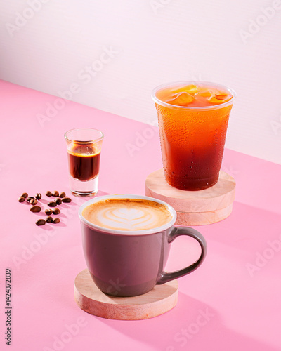 A coffee cup with a shot of espresso and a cup of tea with ice cubes. The coffee is a dark roast and the tea is a fruity blend