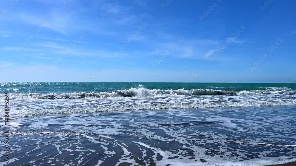 Ocean waves crashing on the beach with clear blue sky