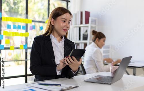 Happy Asian businesswoman working on financial documents in the office. Female accountant doing accounting work and auditing.