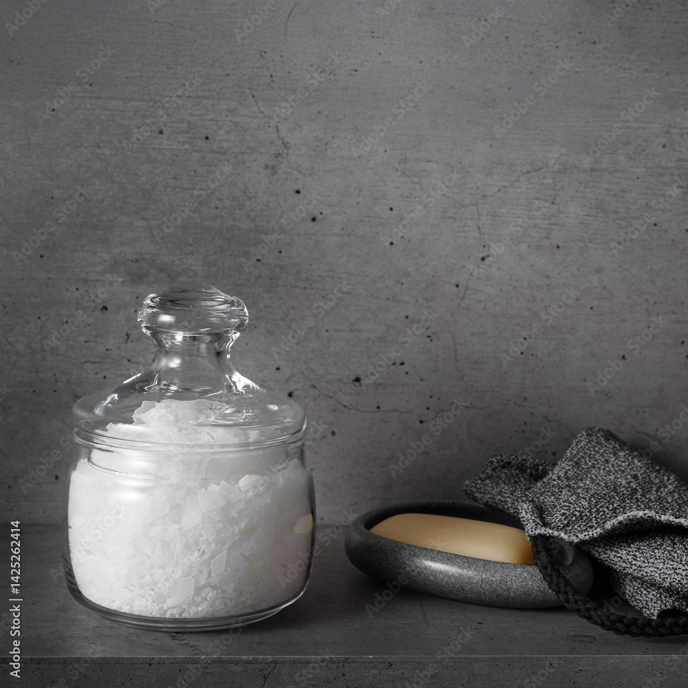 Natural magnesium salt in glass jar, soap, exfoliating loofah, gray bathroom, concrete background. Aesthetic still life. Self-care or sustainable living, Wellness and Body Function Enhancement