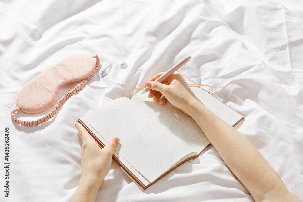 Woman takes notes or makes plan, day results on blank white page of paper in notebook or diary, holds notepad in hands, close-up top view, time for yourself morning or evening before sleep