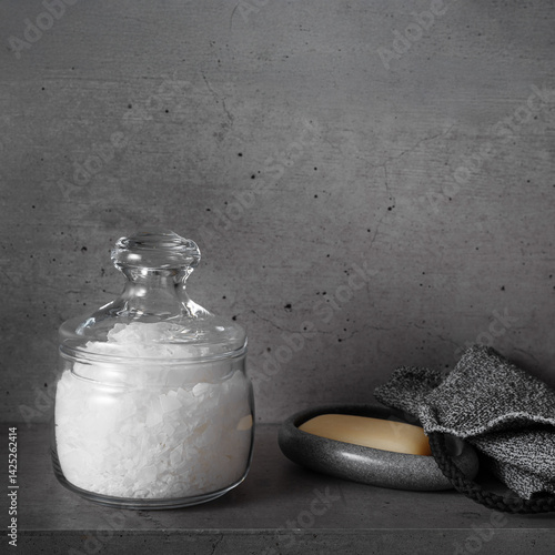 Obraz na płótnie Natural magnesium salt in glass jar, soap, exfoliating loofah, gray bathroom, concrete background. Aesthetic still life. Self-care or sustainable living, Wellness and Body Function Enhancement w salonie