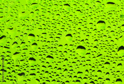 Rain drops on window glass. Natural Pattern of raindrops. Water droplets on a green background.