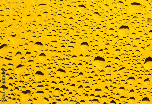 Rain drops on window glass. Natural Pattern of raindrops. Water droplets on a yellow background.