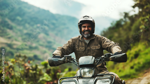 Joyful middle-aged Indian man riding an all-terrain vehicle in a scenic mountainous landscape during a sunny day